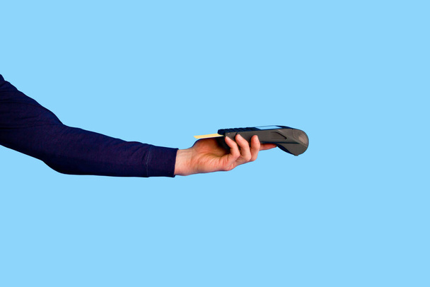 青い背景にクレジットカード決済端末を保持する男性の手.. - 写真・画像