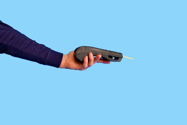 Mano masculina sosteniendo un terminal de pago con tarjeta de crédito sobre un fondo azul
.. - Foto, imagen
