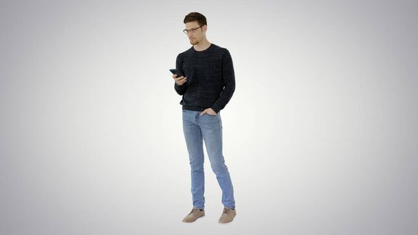 Man with glasses suffering with cough and using his phone on gradient background. - Foto, imagen