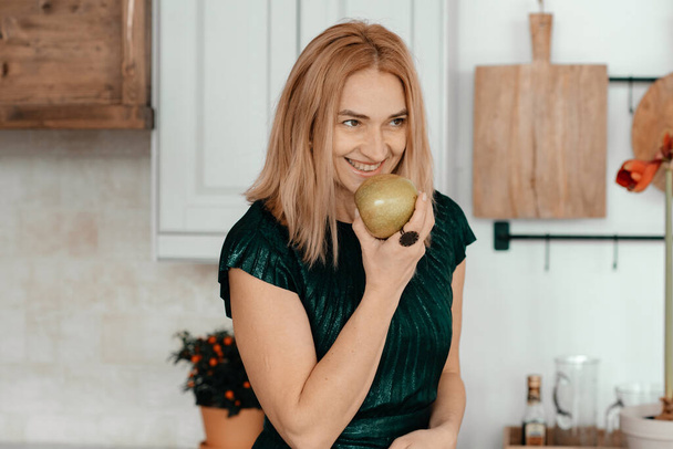 молода красива жінка позує з яблуком на кухні
 - Фото, зображення