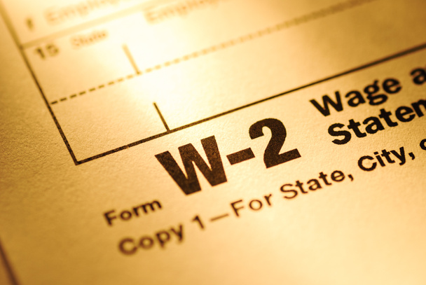 Cierre en un formulario W-2 de declaración de sueldo e impuestos para el Tesoro de los Estados Unidos o IRS con enfoque en el título a la luz amarilla
 - Foto, Imagen