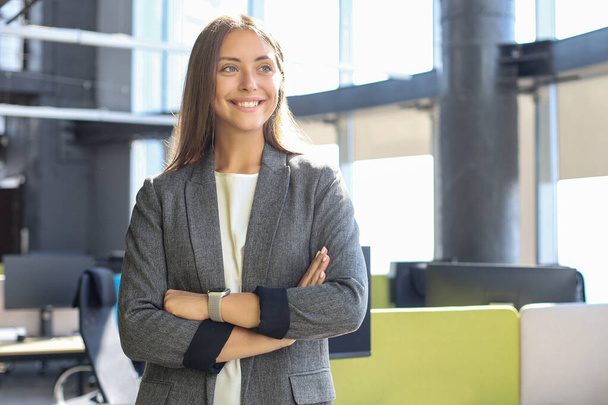 Atractiva mujer de negocios sonriendo mientras está de pie en la oficina - Foto, Imagen