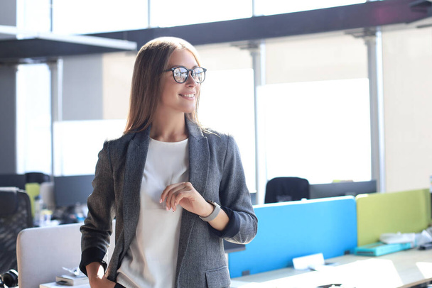 Attraente donna d'affari sorridente mentre in piedi in ufficio - Foto, immagini