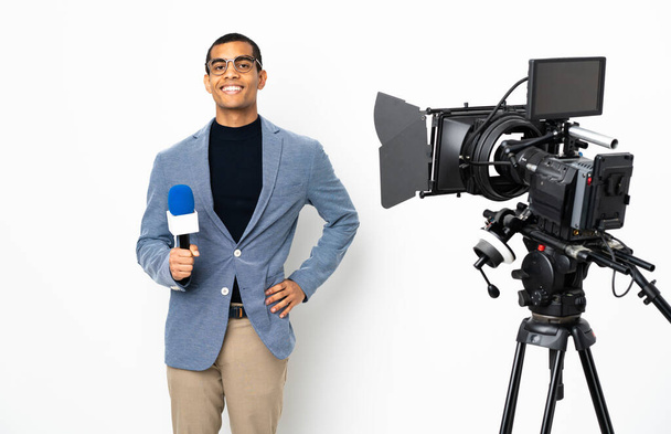 Reporter Afroamerykanin trzyma mikrofon i raportuje wiadomości na odizolowanym białym tle pozowanie z ramionami na biodrach i uśmiechnięty - Zdjęcie, obraz
