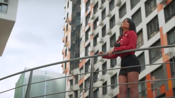 Schöne Frau auf einer Brücke in der Nähe moderner Gebäude - Filmmaterial, Video