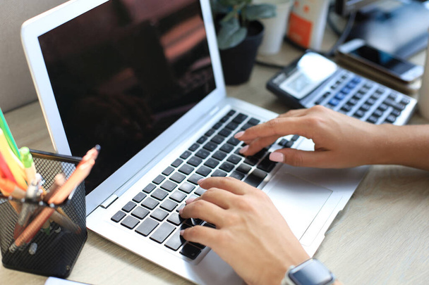 Woman hands pressing keys on a laptop keyboard in office - 写真・画像
