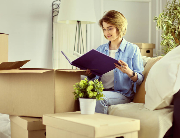 Young woman moving out and packing cardboard box - Foto, Bild