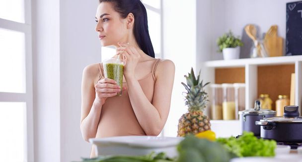 Young woman with glass of tasty healthy smoothie at table in kitchen - Fotoğraf, Görsel