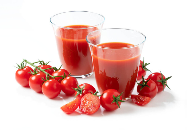 Sok pomidorowy i świeże pomidory umieszczone na białym tle, fotografowane pod kątem. - Zdjęcie, obraz