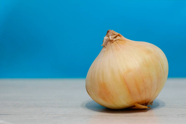 onion head on the table on a blue background - Foto, imagen