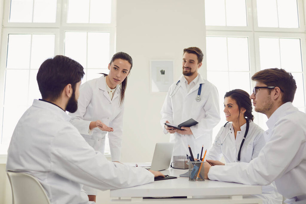Group of practicing doctors in a meeting discuss the diagnosis of a patient standing in a clinic office. - Foto, afbeelding