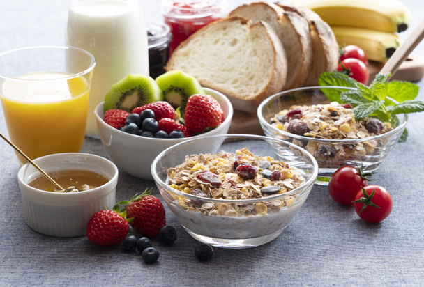 Beelden van een uitgebreid ontbijt van granola, brood, fruit en sap - Foto, afbeelding