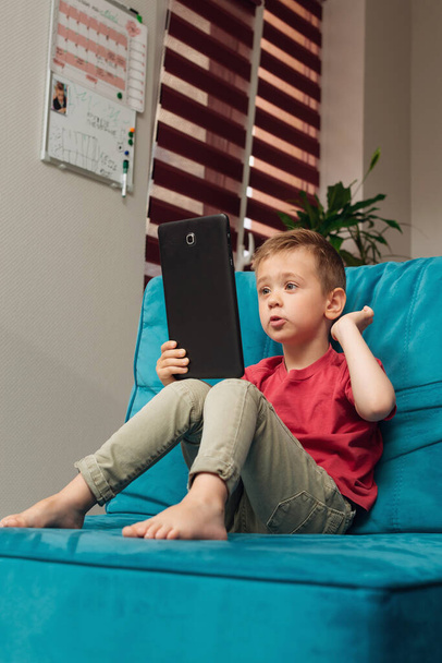 Ένα μικρό αγόρι επικοινωνεί χρησιμοποιώντας tablet - Φωτογραφία, εικόνα