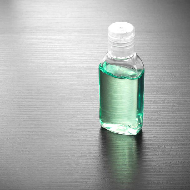 Disinfettante per le mani antibatterico contenente alcol in una bottiglia di plastica. Disinfettante per le mani di colore verde su un tavolo di legno. Gel mano antibatterico
. - Foto, immagini
