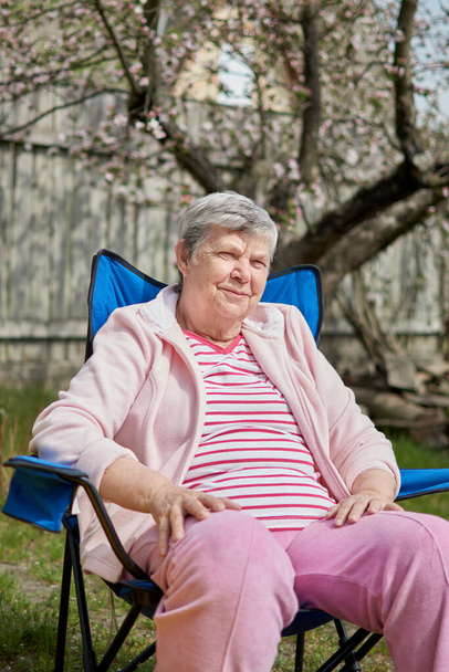 Side head shot view tranquil calm middle aged hoary woman sitting on camping chair alone. Peaceful mindful mature senior grandmother daydreaming relaxing meditating outdors. Enjoy retire. - Photo, Image