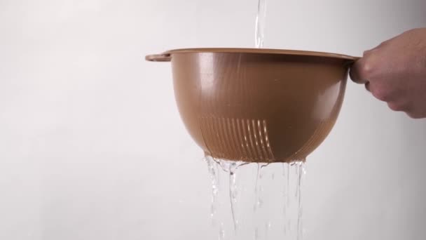 Νερό χύνεται μέσα από ένα σουρωτήρι ή σουρωτήρι - Πλάνα, βίντεο