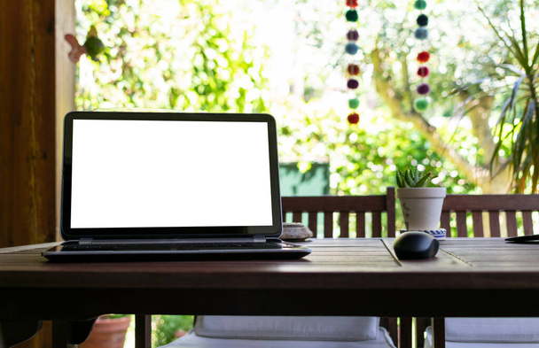Fotografía de un portátil con una plantilla de pantalla para la publicidad, con un jardín en el fondo. Imagen de teletrabajo desde casa
. - Foto, imagen
