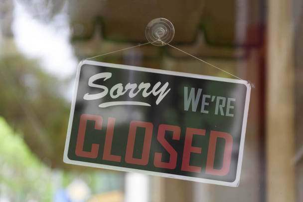 Close-up on an closed sign in the window of a shop saying "Sorry, we're closed". - Photo, Image
