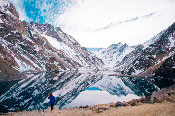 Punapää nuori aikuinen nainen poseeraa edessä Andes Mountains sininen takki ja katselee poispäin kamerasta
. - Valokuva, kuva