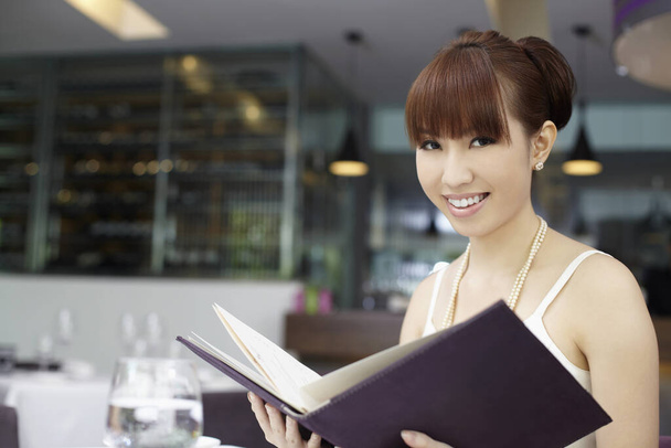 Woman smiling at the camera while holding food menu - Foto, afbeelding