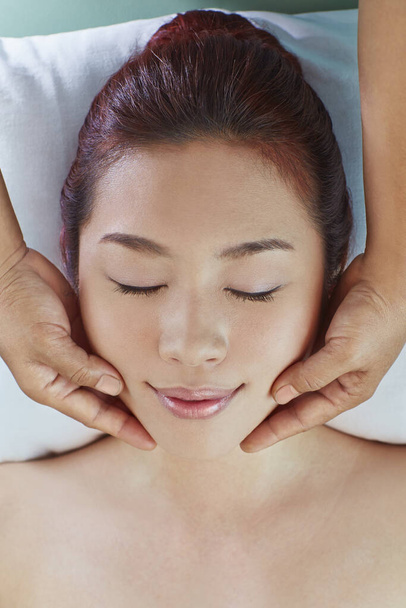 A young woman getting a head massage - 写真・画像