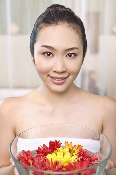 A young woman holding a bowl of flowers - Fotó, kép