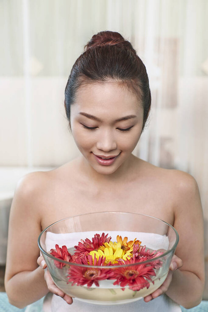 Egy fiatal nő kezében egy tál virággal. - Fotó, kép