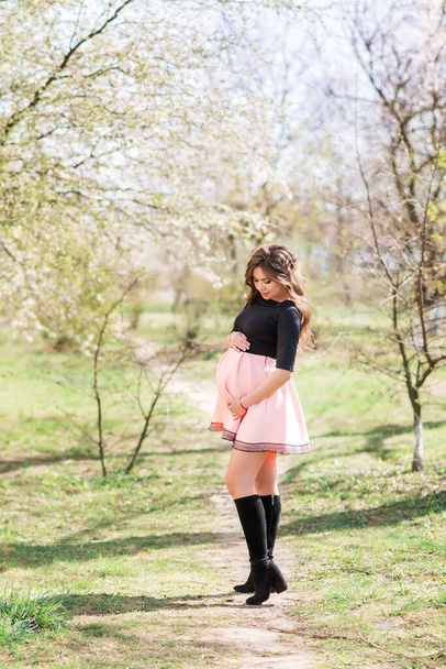 Mooie zwangere vrouw in bloeiende tuin - Foto, afbeelding