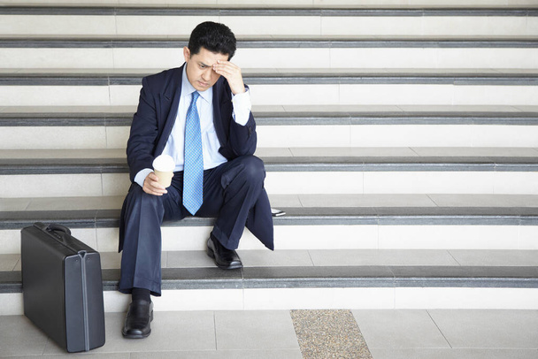 Worried businessman sitting on stairway, contemplating - Фото, зображення