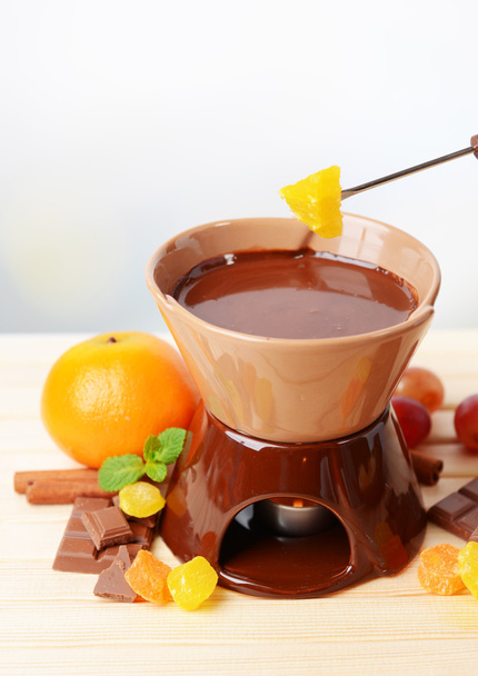 Chocolate fondue with fruits, on wooden table, on light background - Fotoğraf, Görsel