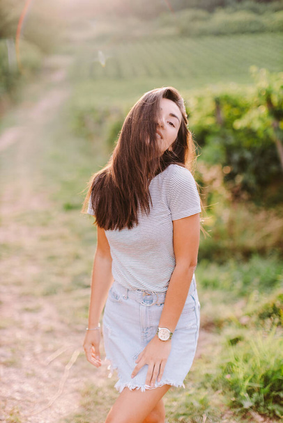 muotokuva naisen rentouttava maaseudulla kesäaikaan. Valkoihoinen pitkät hiukset nainen rentoutua maaseudulla viinitarha-alueella auringonlaskun aikaan. Italia - Valokuva, kuva