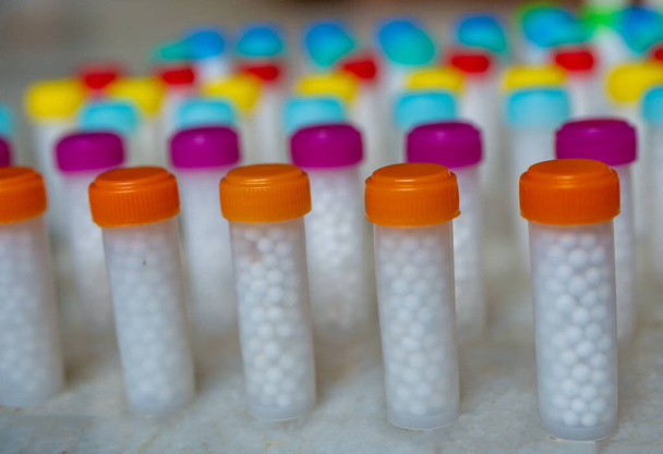 Colorful plastic Bottles filled with white homeopathic pills/globules - Photo, image