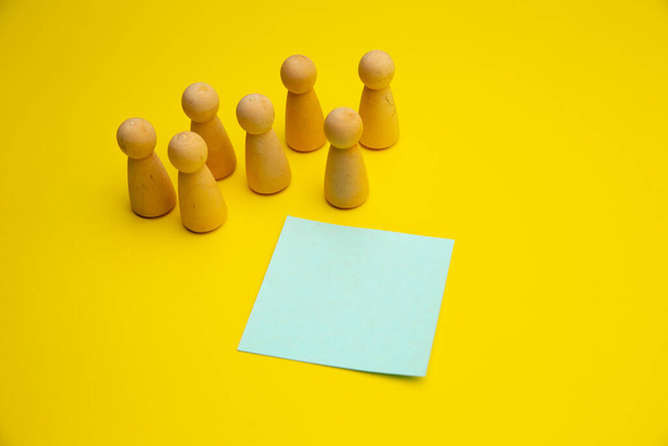 Teamwork, teambuilding mockup, company structure. Wooden figures stands near blue sticky note, place for text - Photo, Image