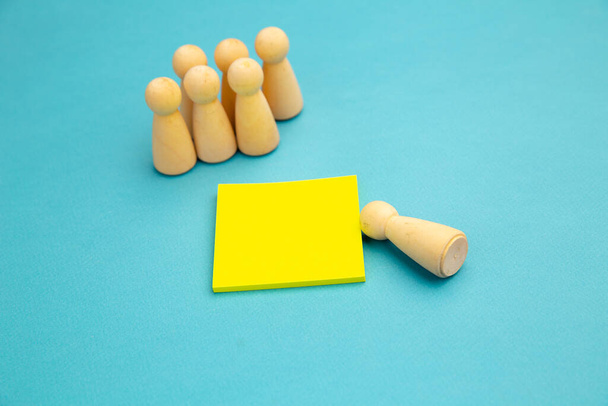 Grupo de personas y una persona separada. Peones de madera con nota adhesiva amarilla para escribir
 - Foto, Imagen