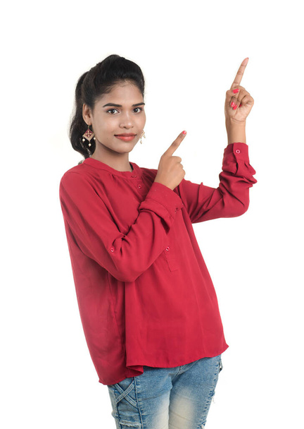 Young smiling girl pointing fingers to copy space on a white background - Фото, изображение