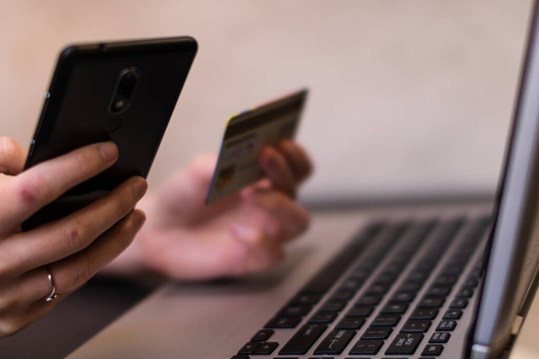 Hitelkártyát tartó kezek okostelefonnal és laptoppal. Online vásárlás, online fizetés koncepciója - Fotó, kép