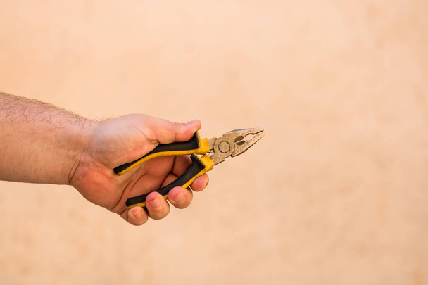 Tools for repair and building. Hand holding pliers on blurred background - Photo, Image