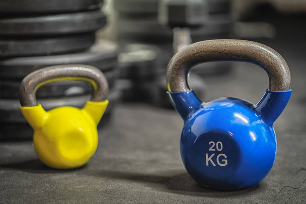 Obrázek modré a žluté barevné kettlebell závaží v tělocvičně - Fotografie, Obrázek
