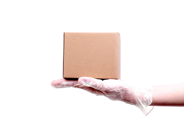 Die weibliche Hand in einem transparenten Einweghandschuh hält einen Karton - sichere Lieferung von Waren, isoliert auf weißem Hintergrund, Kopierraum - Foto, Bild