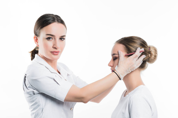A cosmetologist examines the patient face and plans to perform a series of cosmetic procedures - Фото, зображення