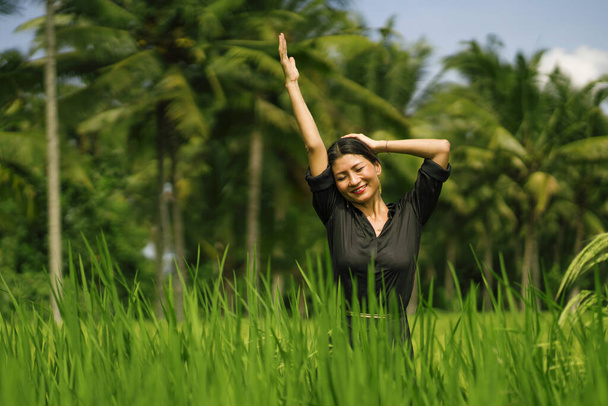 outdoors portrait of attractive and happy Asian Korean woman 40s or 50s enjoying nature excited and carefree playful at tropical rice field during Summer holidays tourist travel - Photo, image