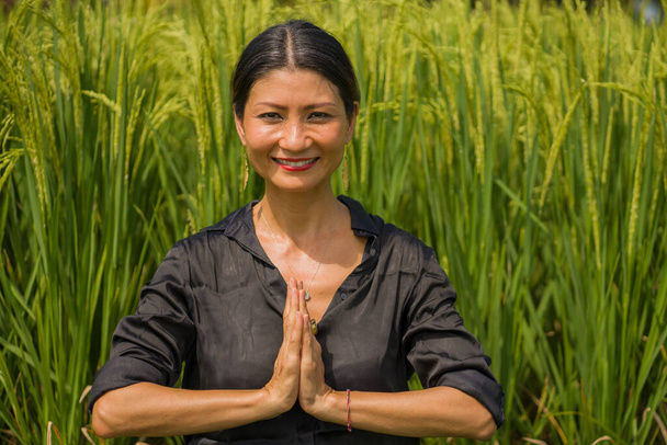 yoga al aire libre y meditación en el campo de arroz: atractiva y feliz mujer japonesa asiática de mediana edad que disfruta del yoga y la relajación en relación con la naturaleza en un estilo de vida y bienestar saludables
 - Foto, Imagen