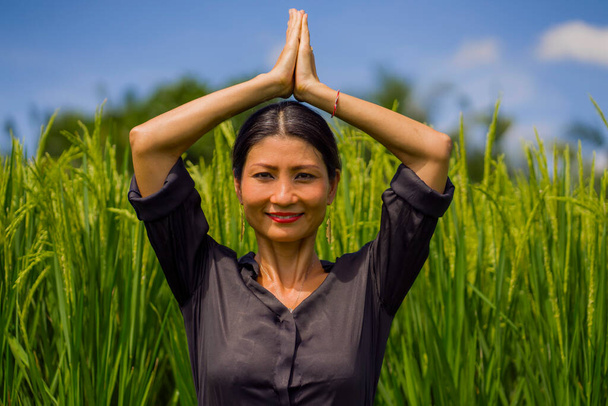 jogi na świeżym powietrzu i medytacji na polu ryżu - atrakcyjne i szczęśliwe Azji w średnim wieku japońskiej kobiety korzystających jogi i relaksu w związku z naturą w zdrowym stylu życia i wellness - Zdjęcie, obraz