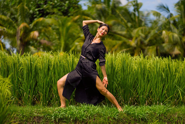 Yoga und Meditation im Freien auf dem Reisfeld - attraktive und glückliche Japanerin mittleren Alters, die Yoga und Entspannung in Verbindung mit der Natur in gesundem Lebensstil und Wellness genießt - Foto, Bild