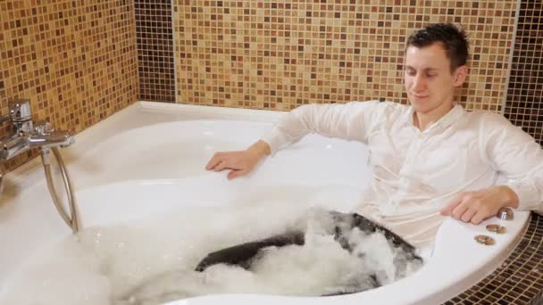 mbusinessman an in clothes is lying in a Jacuzzi. Relax after a hard day - Footage, Video