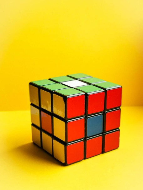 Rubik's Cube on a yellow background. Vertical image. Face colors: red, green, yellow. Vintage thing. - Foto, immagini