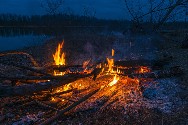 Hoguera de fuego crepuscular. Invitar a la fogata a acampar en la noche
 - Foto, imagen