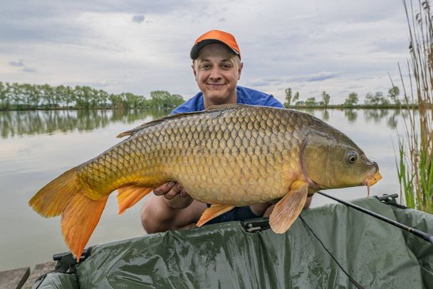Pesca de carpas. Pescador con trofeo de pescado en las manos en el lago
 - Foto, imagen
