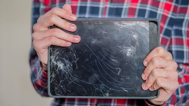 Un homme tient une tablette avec un écran cassé - Photo, image