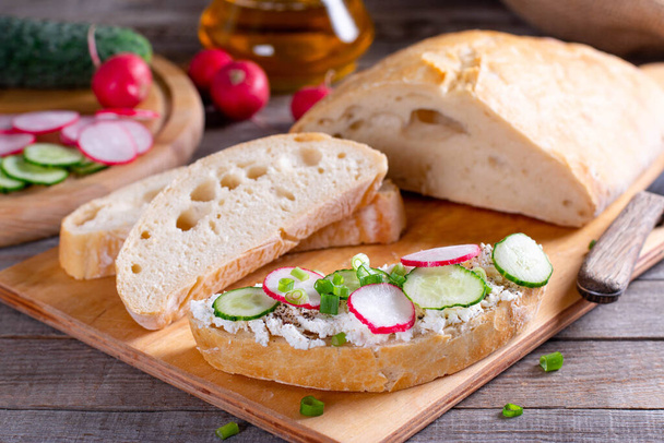 broodjes met komkommers, radijs en roomkaas op houten bord, Closeup, Ontbijt of lunch concept - Foto, afbeelding